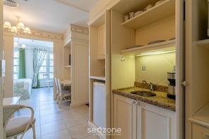 Cocina con lavabo, encimera y armarios.  Hay una zona de comedor con sillas y una mesa.