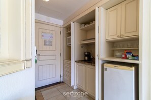 Cocina compacta con armarios blancos, un refrigerador y un microondas.
