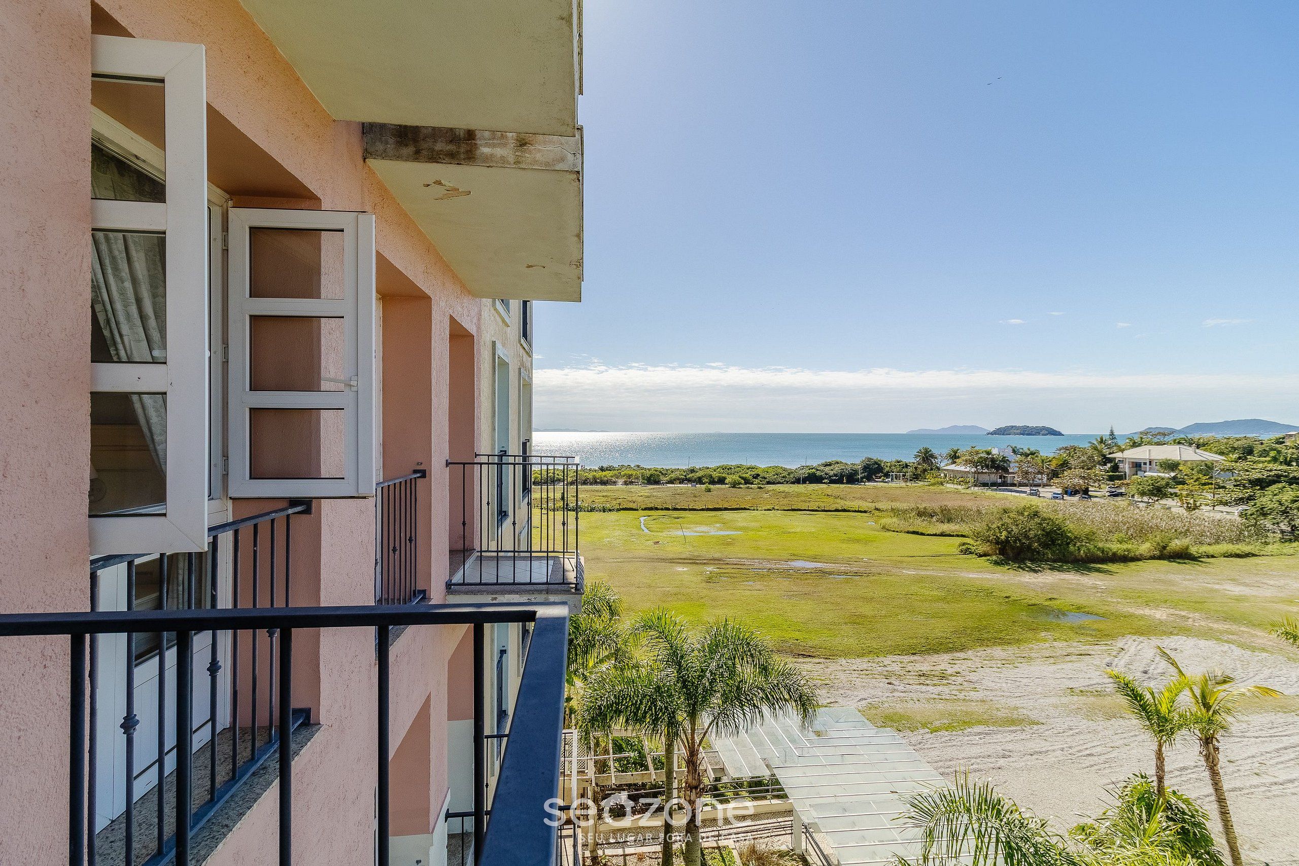 Uma varanda com vista para a praia e montanhas ao longe.