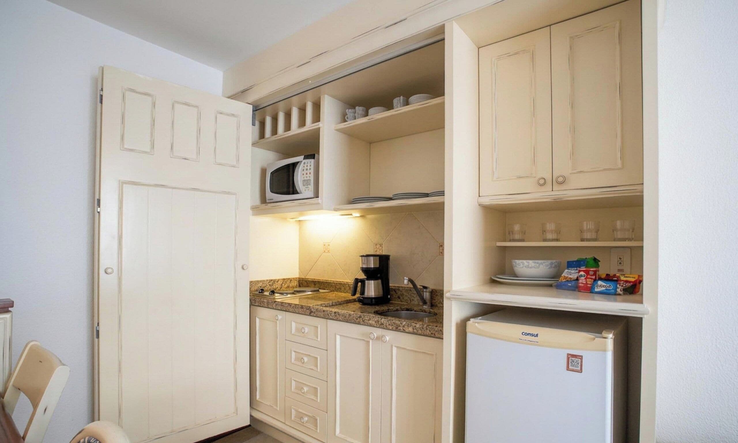A compact kitchen with a microwave, coffee maker, and a refrigerator.