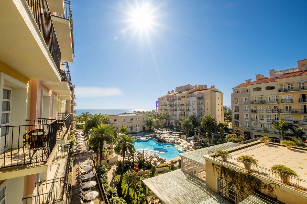Un hotel con piscina en la azotea, balcones y vista al mar.