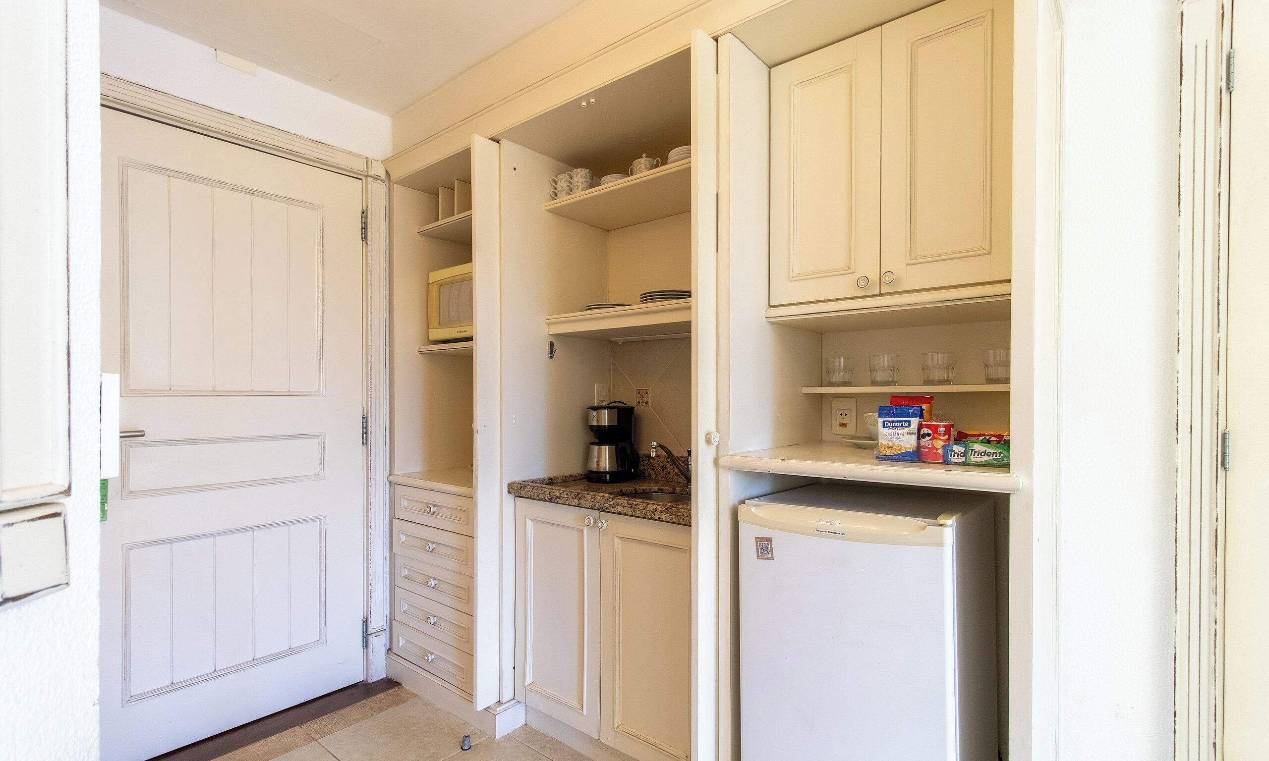 A kitchen with white cabinets, a microwave, a coffee maker, and a refrigerator.