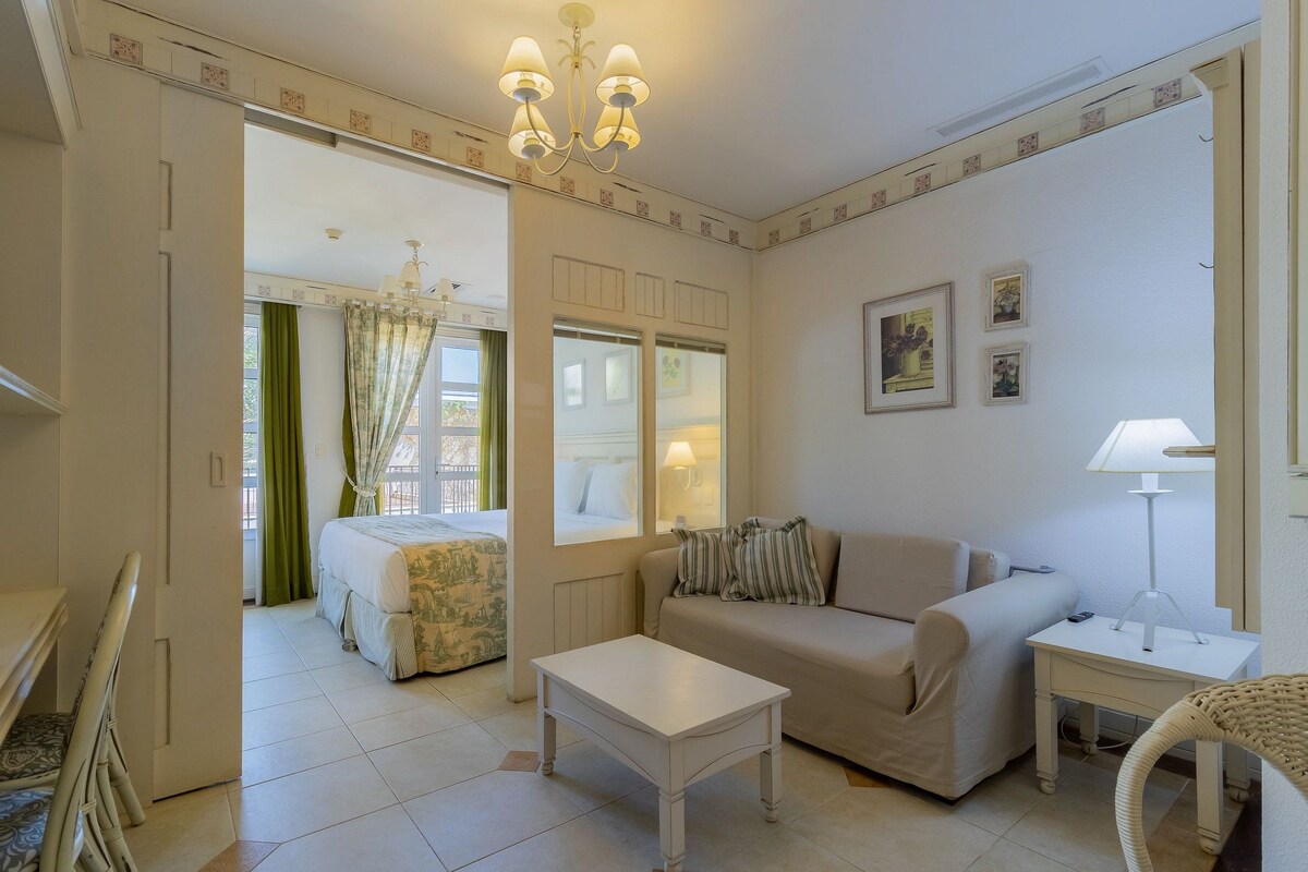 Una habitación con una cama, un sofá, una mesa, una lámpara y una silla.