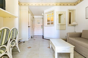 A hallway with a white sofa, a white table, and striped chairs. - Confortáveis Studios no IL Campanario Resort ILCJR (Florianópolis)