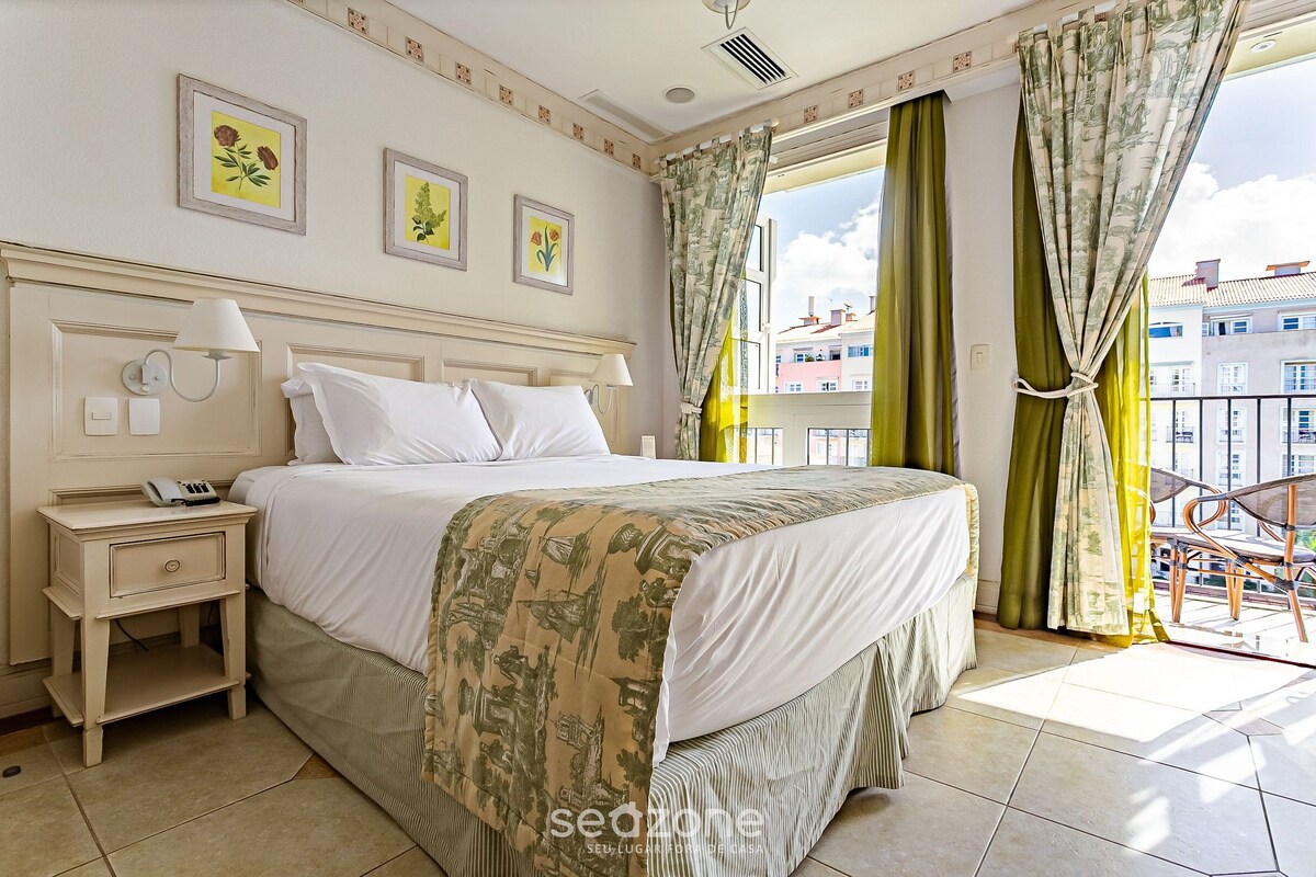 Un dormitorio con cama, mesita de noche, lámpara y cortinas.