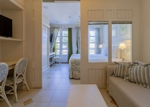 Una habitación de hotel con cama, escritorio y silla, sofá y ventana con cortinas.