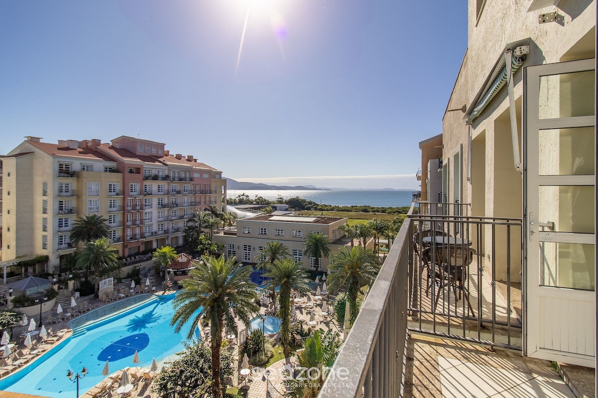 Un hotel con piscina, varias edificaciones y vista al mar.