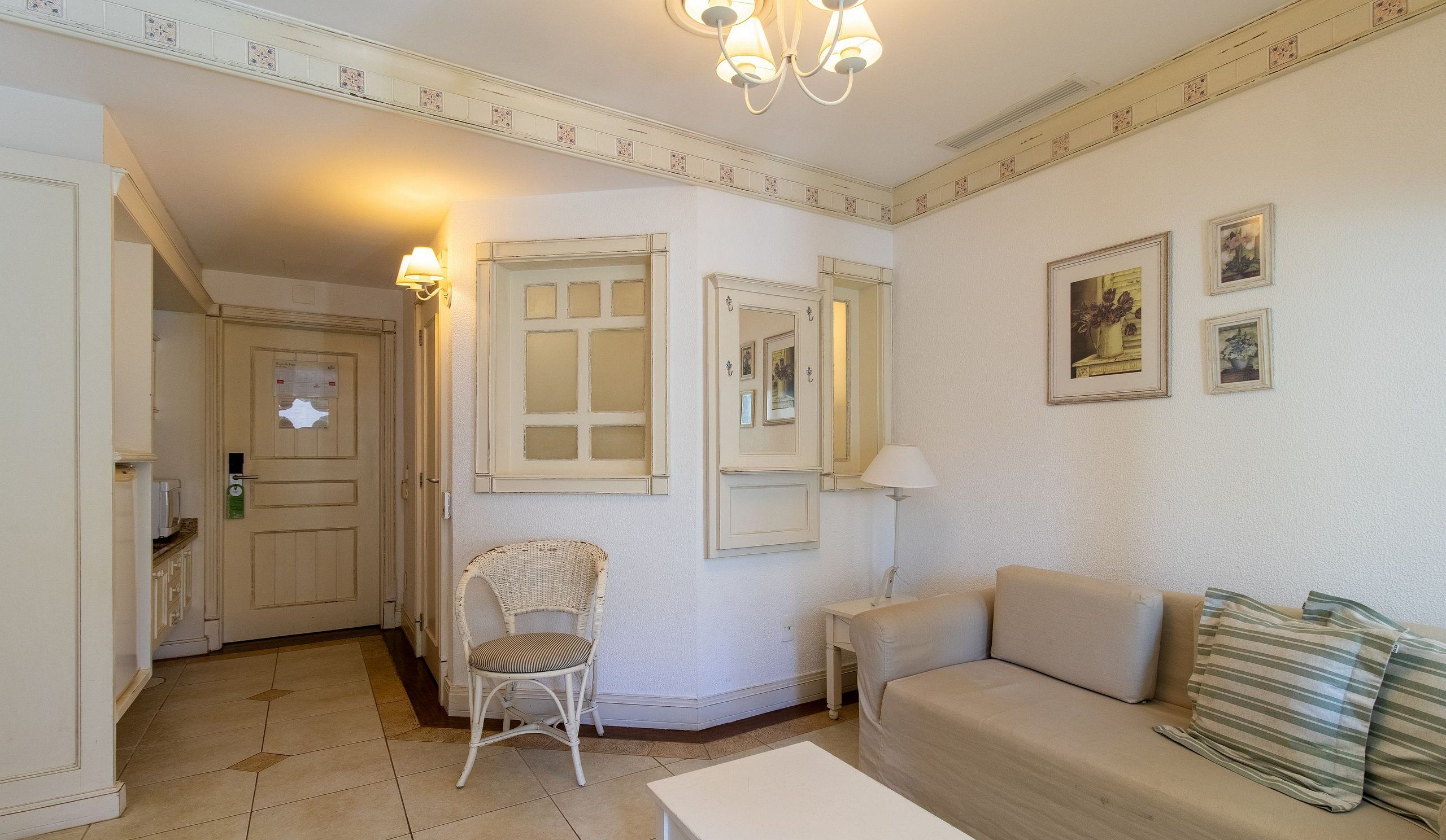 A room with a sofa, a chair, a table, and a door with a mirror.