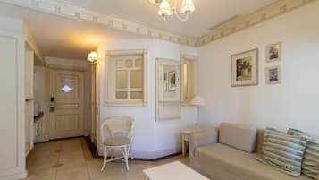 Una habitación con sofá, sillón, mesa y puerta con espejo.