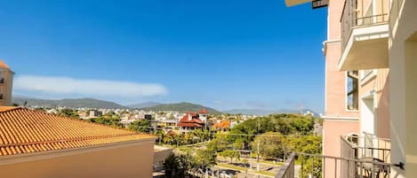 A balcony with a view of a residential area, including houses with red roofs and a mountain in the distance.