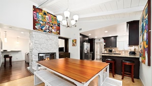 A spacious kitchen with a central island, a stone fireplace, and modern cabinetry. - Beautiful 5bd 3ba Private Resort Pool and HotTub, Waterslide, CloseTo Disneyland (Anaheim)