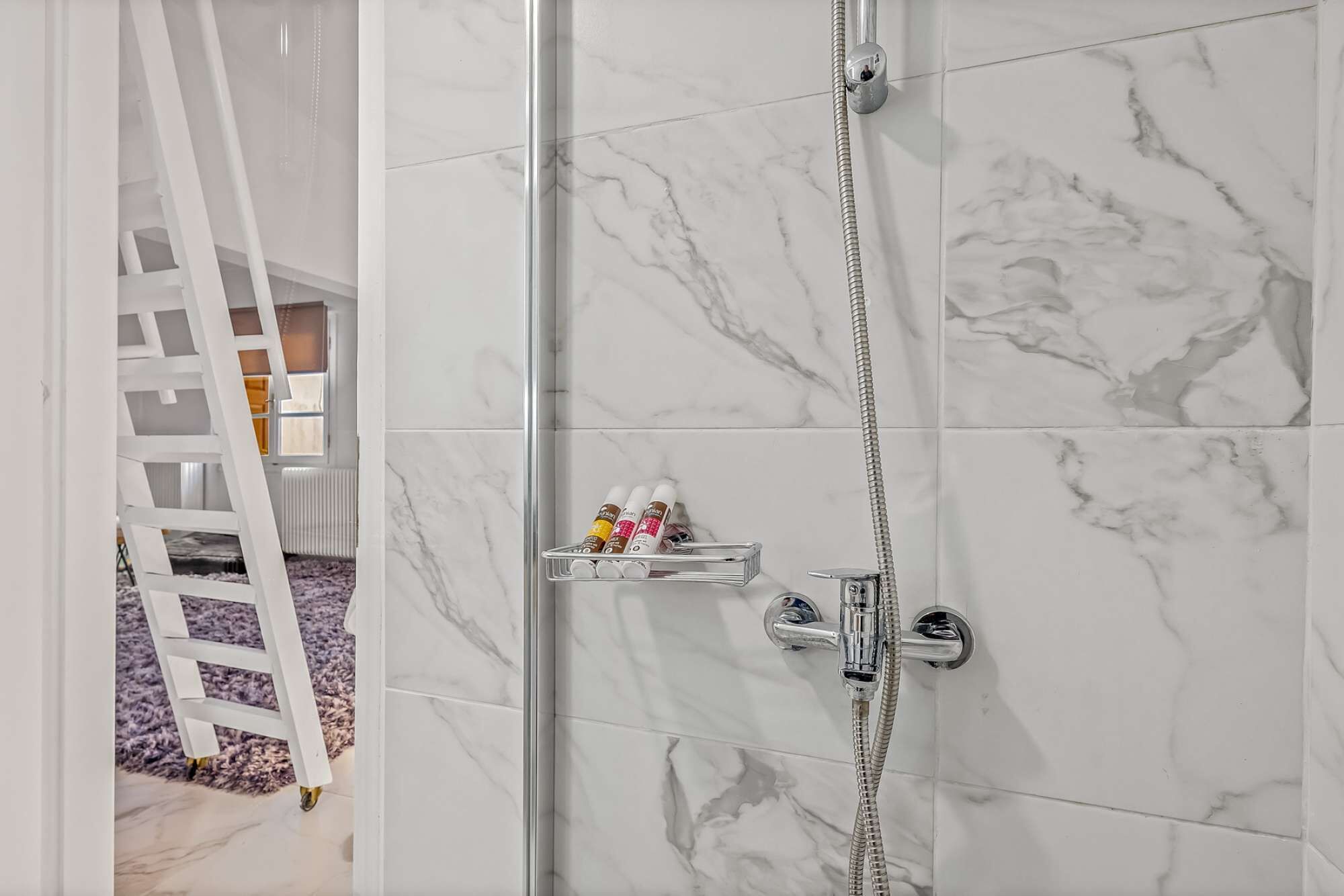 Ein modernes Badezimmer mit einer Duschkabine aus Glas, Marmorfliesen und einem Chrom-Duschkopf.