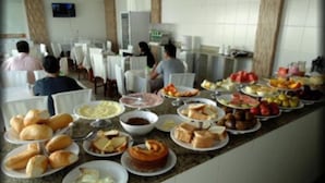 A buffet with various food items and a seating area with tables and chairs.