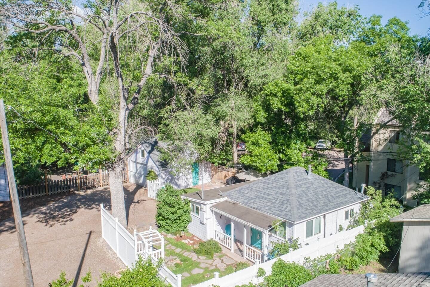 Un quartier résidentiel avec une maison dotée d’un patio couvert, d’une cour clôturée et d’un petit abri de jardin.