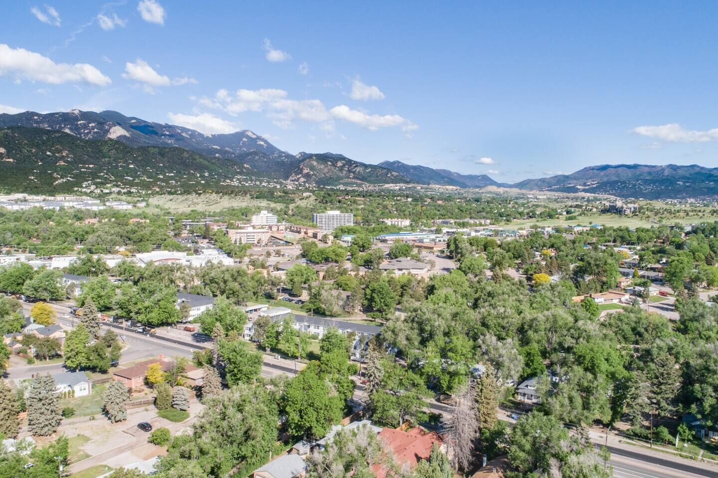 A town with a mix of residential and commercial buildings, surrounded by mountains and greenery.
