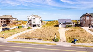 A coastal residential area with houses, a road, and a beach in the background.