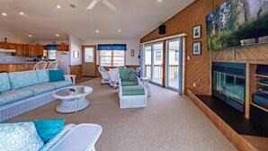 A spacious living area with a sofa, chairs, a coffee table, a fireplace, and a television mounted on the wall.