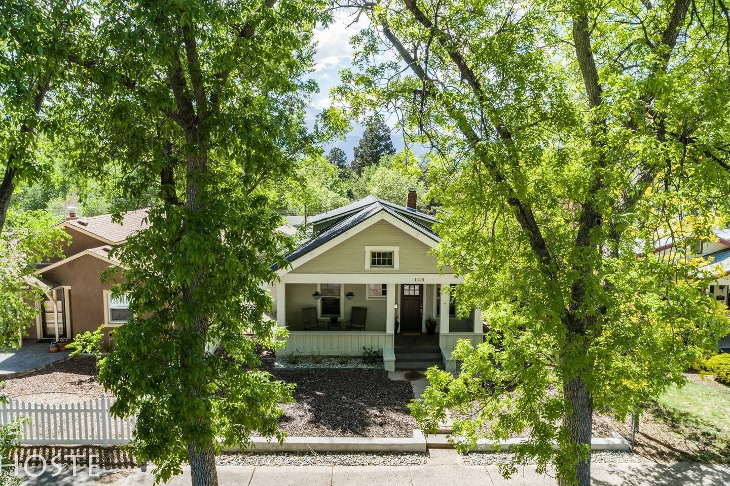 A single-story house with a front porch, surrounded by trees.