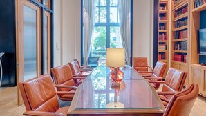A conference room with a glass table, leather chairs, a lamp, and bookshelves with books and a TV. - National at Metropolitan Park (Arlington)