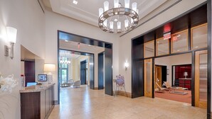 A spacious lobby with a reception desk, seating area, and a chandelier. - National at Metropolitan Park (Arlington)