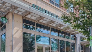 A Starbucks store with a modern glass facade, outdoor seating, and a clear view of the surrounding area. - National at Metropolitan Park (Arlington)