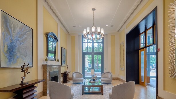 A spacious lobby with a grand chandelier, a fireplace, and a large window offering a view of the outdoors. - National at Metropolitan Park (Arlington)
