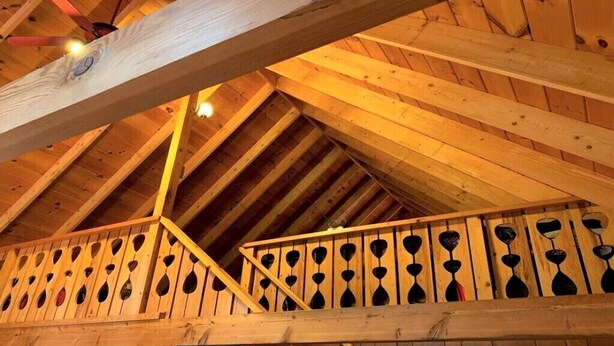 Un balcón de madera con varios maceteros colgantes.