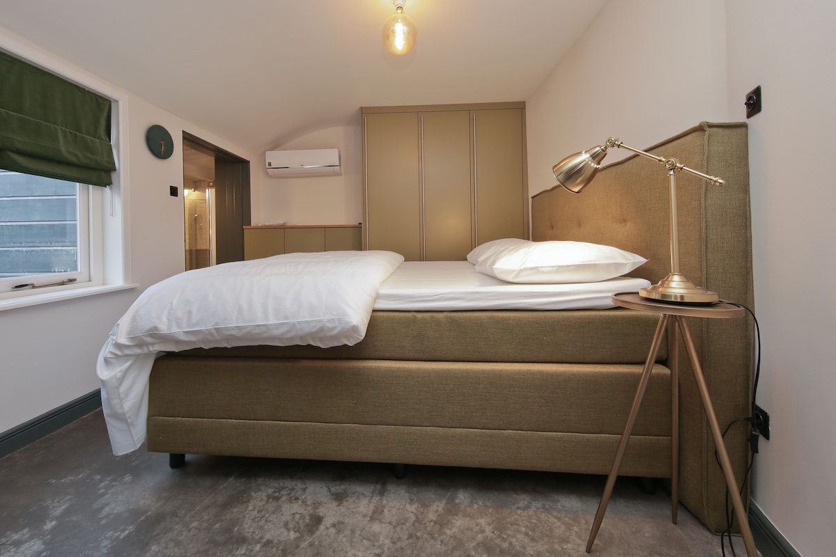 Une chambre à coucher avec un lit, une lampe de chevet, une armoire et une fenêtre.