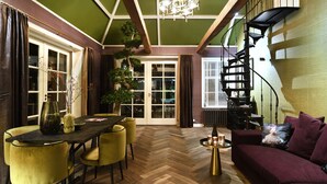 A dining area with a herringbone floor, a wooden table, and yellow chairs. - Hotel Suites Wilma J (Vinkeveen)