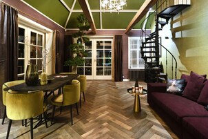 Uma área de refeições com piso em padrão herringbone, uma mesa de madeira e cadeiras amarelas.