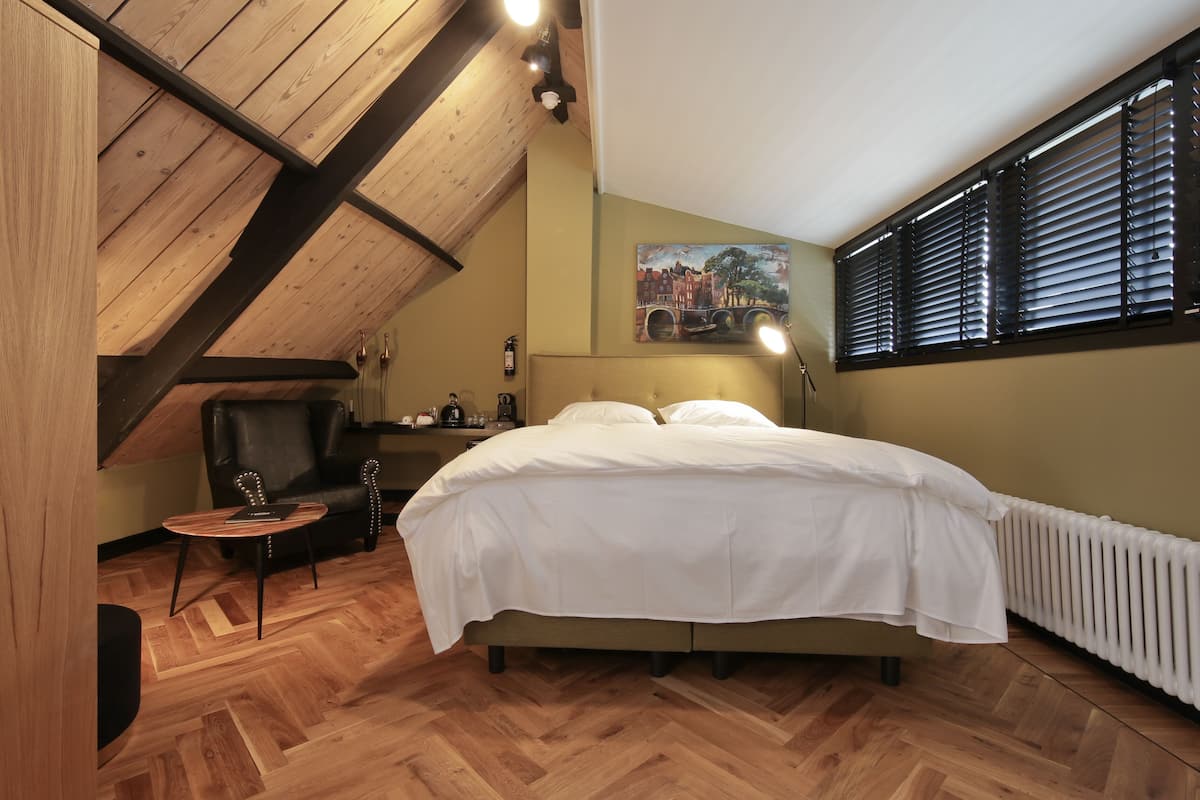 Une chambre à coucher avec un grand lit, un plafond en bois, un radiateur et un tableau accroché au mur.