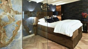 Un dormitorio moderno con una cama grande, un separador de vidrio y una pared decorativa.
