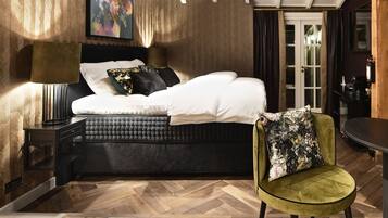 A modern bedroom with a bed, a green chair, a nightstand, and a lamp.