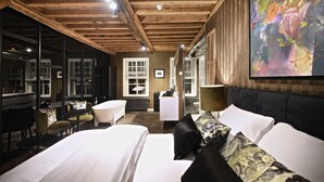 A hotel room with a large bed, a sitting area with a table and chairs, a large mirror, and a painting on the wall. - Hotel Suites Wilma J (Vinkeveen)