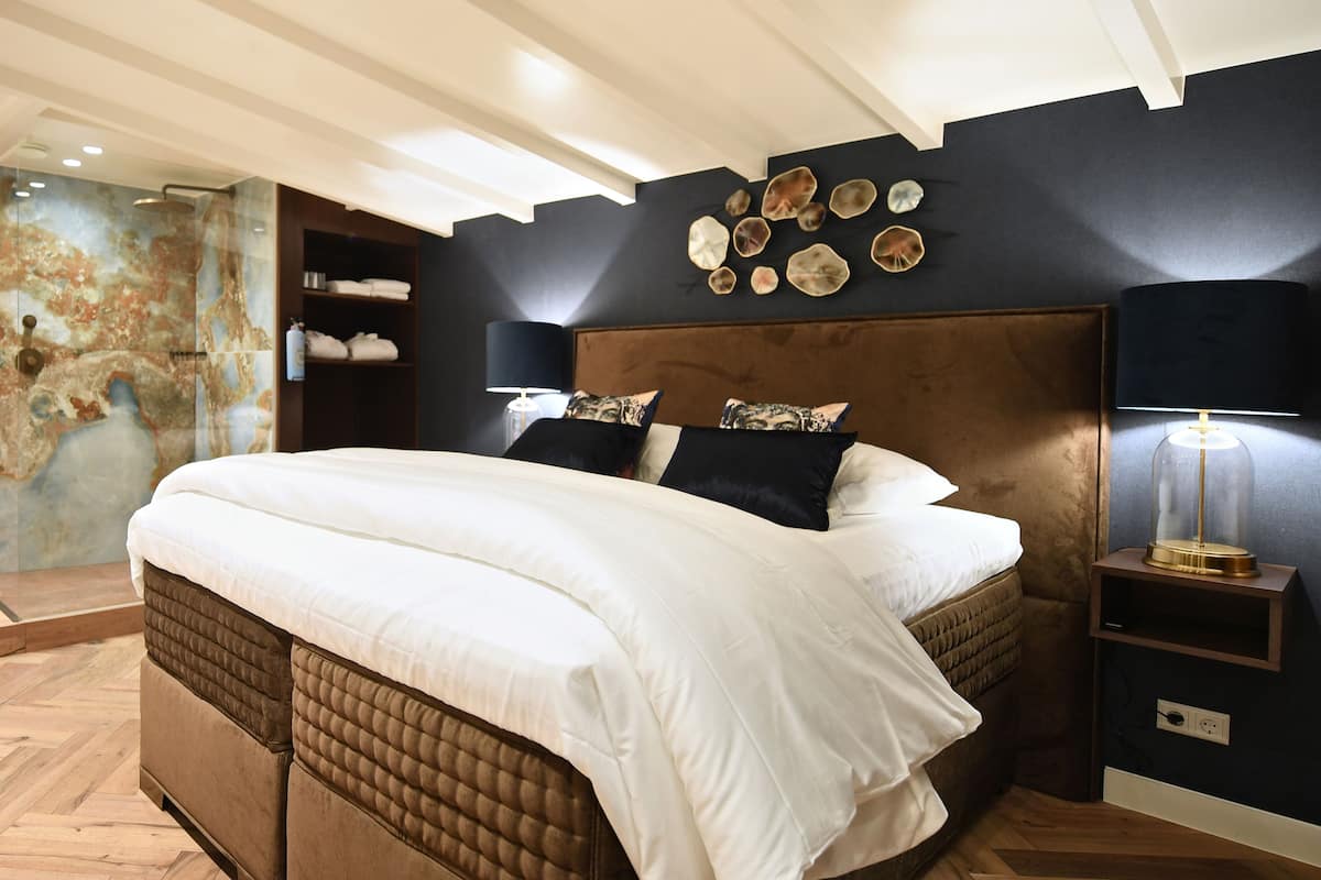 Un lit bien fait, avec une tête de lit, une table de chevet avec une lampe et un mur décoré de coquillages.