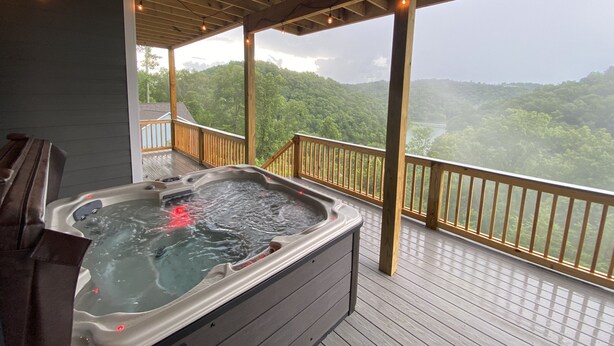 Un jacuzzi en una terraza de madera con vistas a un paisaje boscoso.