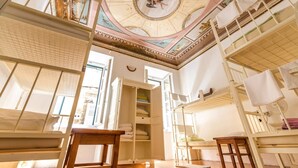 A room with bunk beds, a wooden table, and a ceiling with intricate designs.