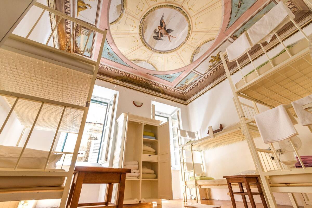 A room with bunk beds, a wooden table, and a ceiling with intricate designs.