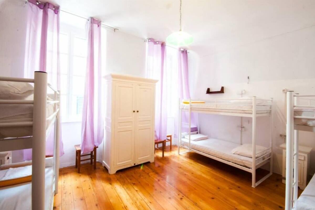 A room with bunk beds, a wardrobe, and a small table.