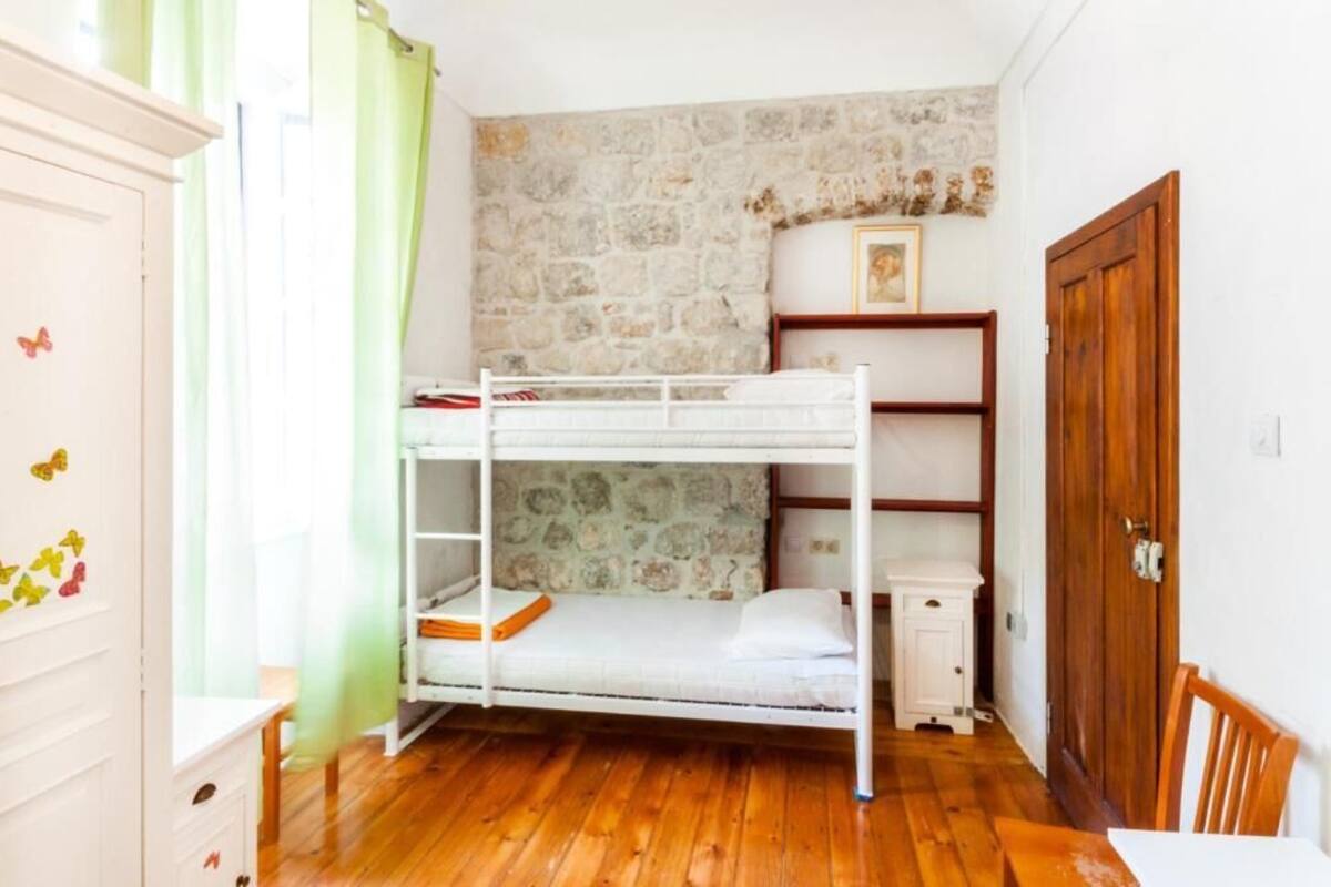 A bunk bed in a room with a stone wall, wooden floor, and a wooden door.