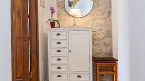 A wooden door, a white cabinet with drawers, a round mirror, a small stool, and a potted plant.