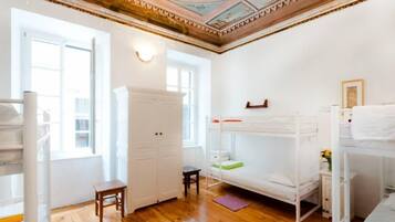 A room with bunk beds, a wardrobe, a small table, and a window.