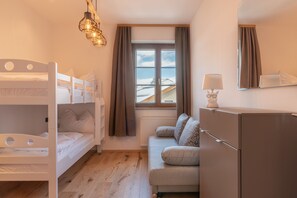 A cozy room with bunk beds, a sofa, a refrigerator, and a window with curtains.