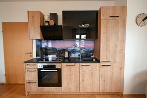 A modern kitchen with wooden cabinets, a built-in oven, a coffee maker, and a decorative backsplash.