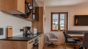 Eine moderne Küche mit Holzschränken, einer schwarzen Arbeitsplatte und einem Essbereich mit Tisch und Stühlen.