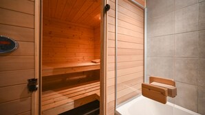 Een houten sauna met een bankje en een kleine tafel.