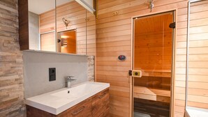 Een moderne badkamer met een houten wastafelmeubel, een glazen douchecabine en een accentmuur van steen.