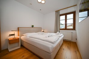 A hotel room with a large bed, bedside tables, a window with curtains, and a radiator.