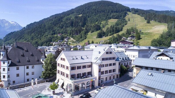 Eine Stadt mit traditioneller Architektur, darunter ein markantes Gebäude mit Schrägdach und ein kleineres Gebäude mit Flachdach.