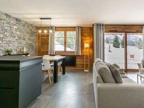 A modern kitchen with a stone wall, wooden accents, and a view of a snowy landscape through large windows.